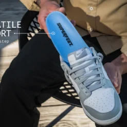 Close-up of a gray Nike sneaker being held, featuring a bright blue insole labeled SUPERFLEET to emphasize versatile support for every step.